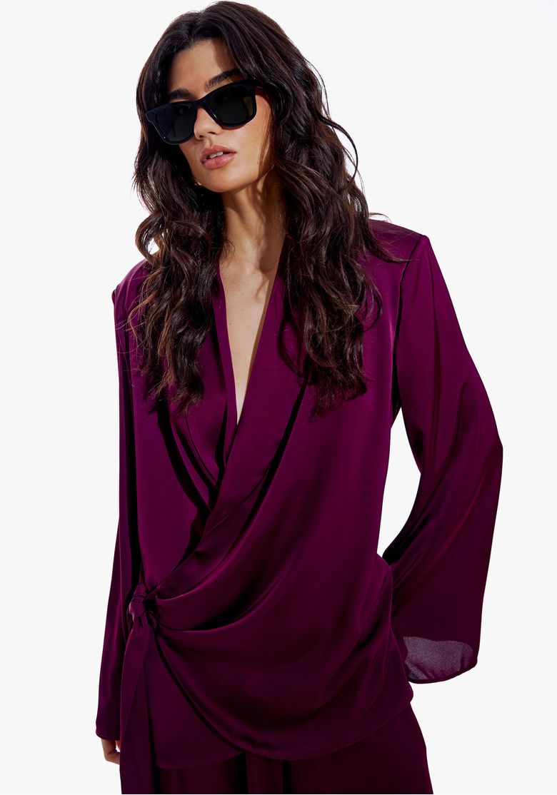 Conjunto blazer de cetim vinho com faixa e calça pantalona larga em fundo branco, look noturno elegante