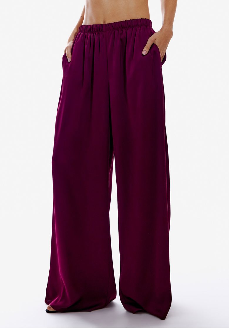 Detalhe da calça wide leg de cetim vinho, mostrando o cós elástico e bolsos.