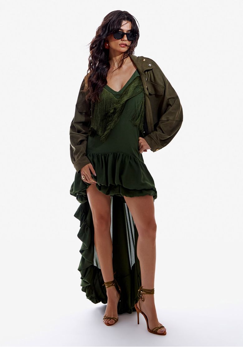 Modelo usando vestido mullet verde escuro com franjas e jaqueta.