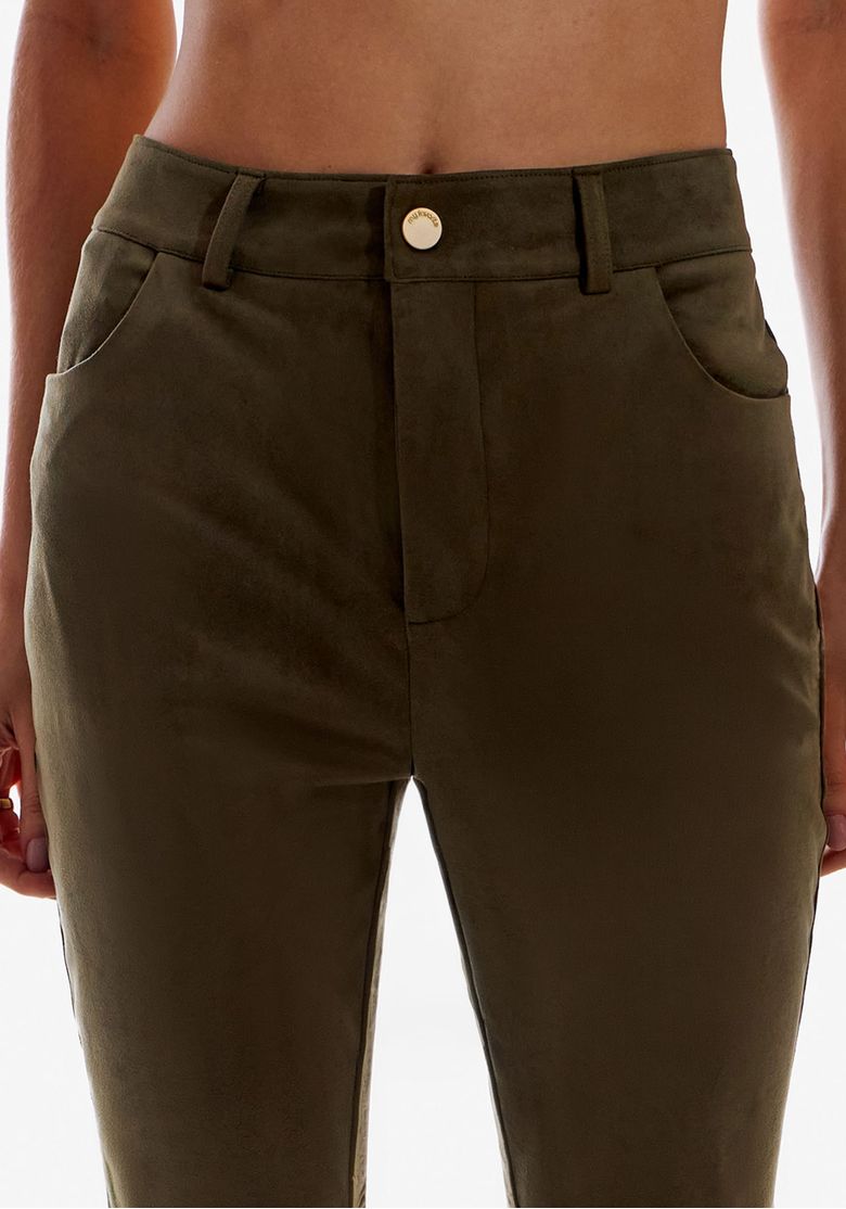 Detalhe frontal do cós e bolso da calça suede verde, botão no cós e bolso curvo funcional