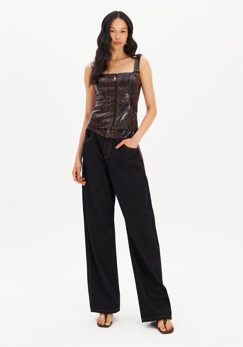 Modelo usando calça jeans carpenter preta cintura média vista frontal, perna larga e comprimento longo com cós em estampa snake