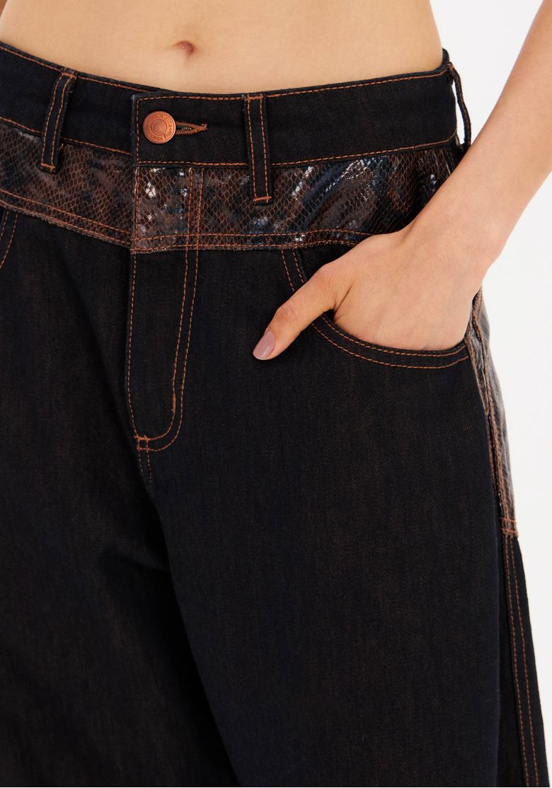 Close do cós e bolso frontal da calça com aplicação em estampa snake e pespontos marrons contrastantes