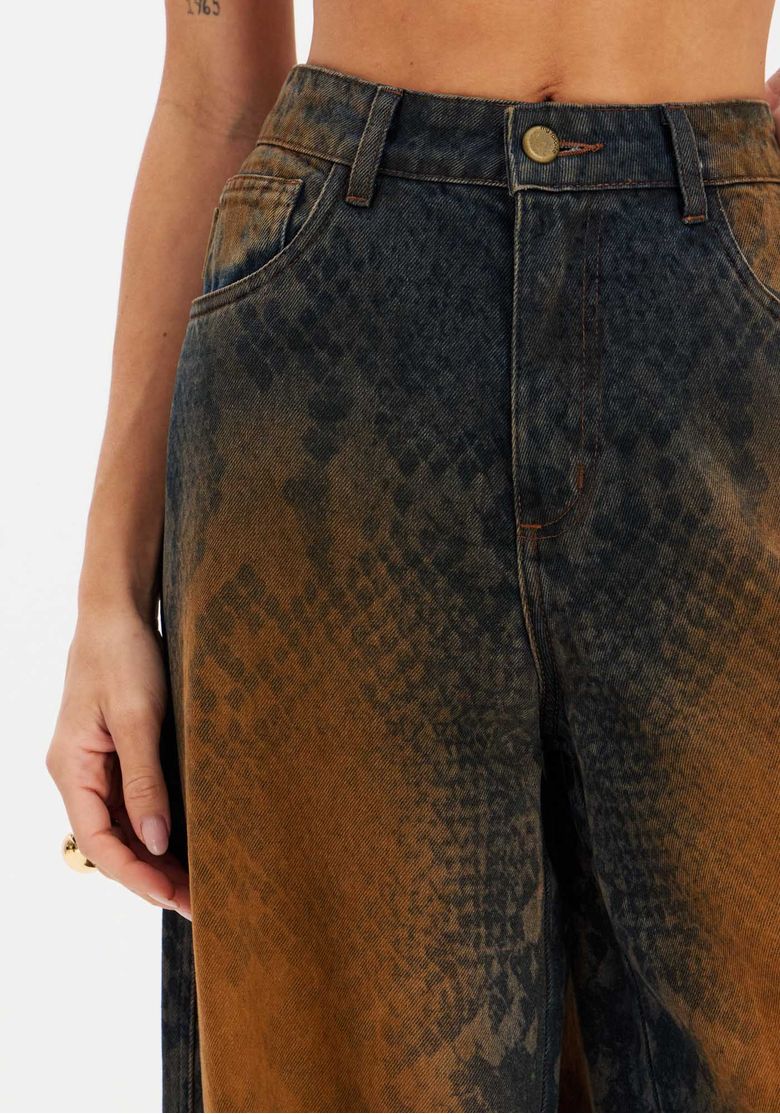 Vista posterior da calça jeans relaxada com bolsos traseiros, estampa degradê snake, barra longa e caimento solto.