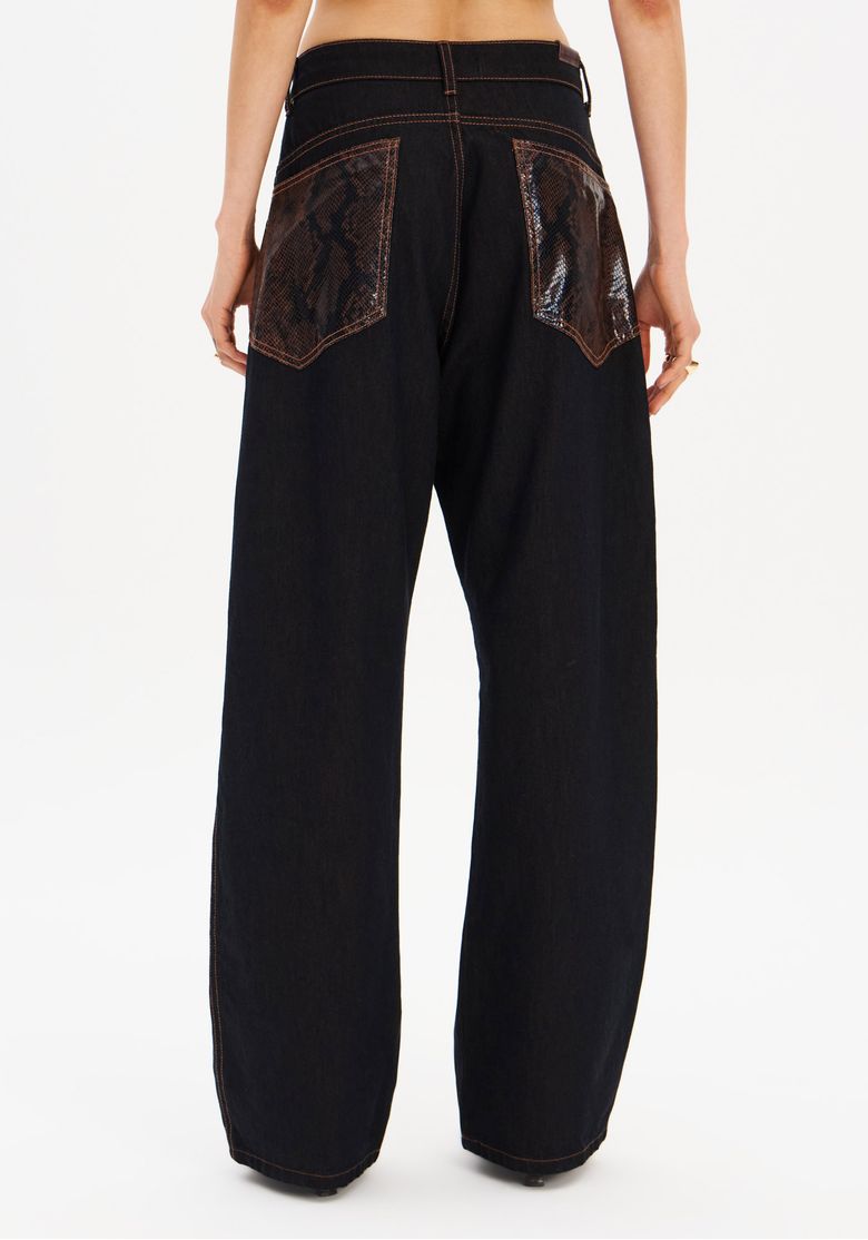 Calça jeans carpenter preta vista de costas, silhueta de perna larga e comprimento longo com detalhes snake nos bolsos