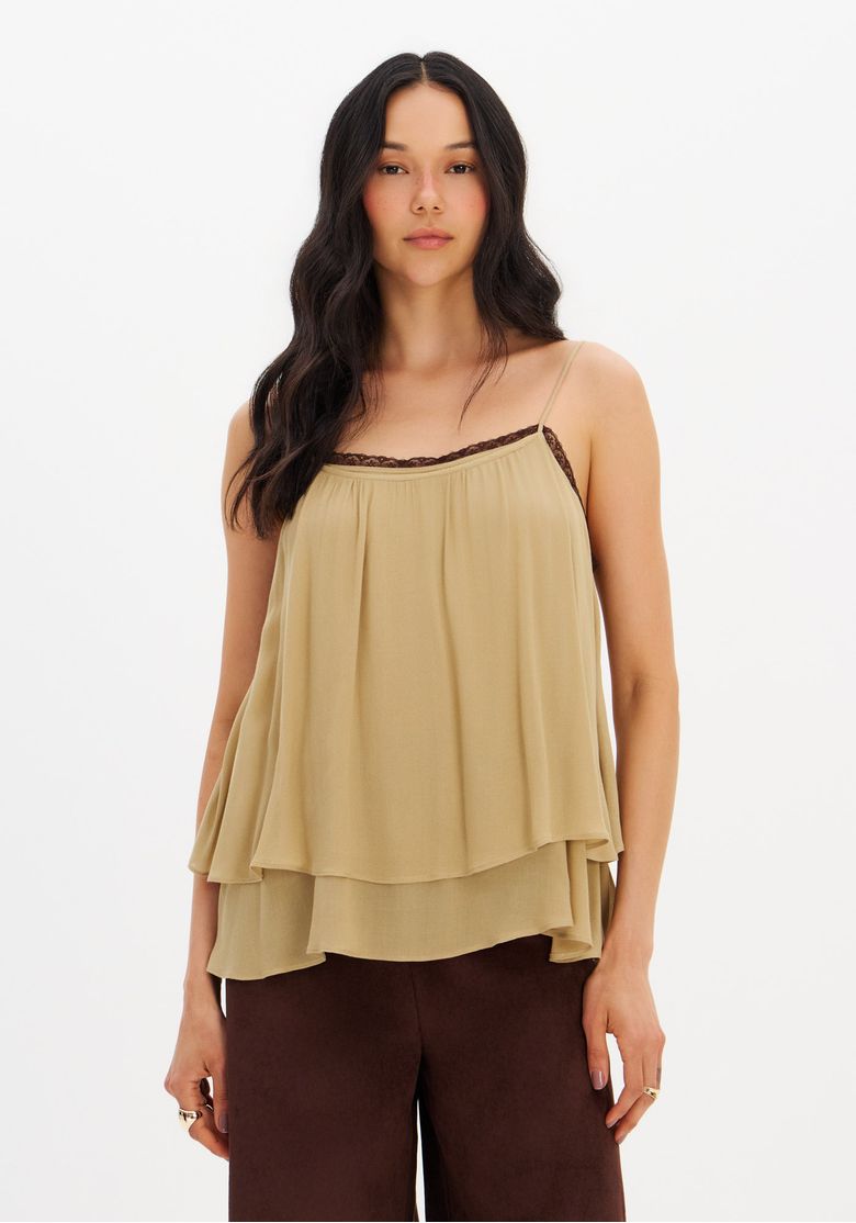 Modelo-vestindo-blusa-bege-ampla-de-viscose-com-alcas-finas-e-renda-no-decote-visao-frontal-em-corte-medio-com-camadas-de-babados.