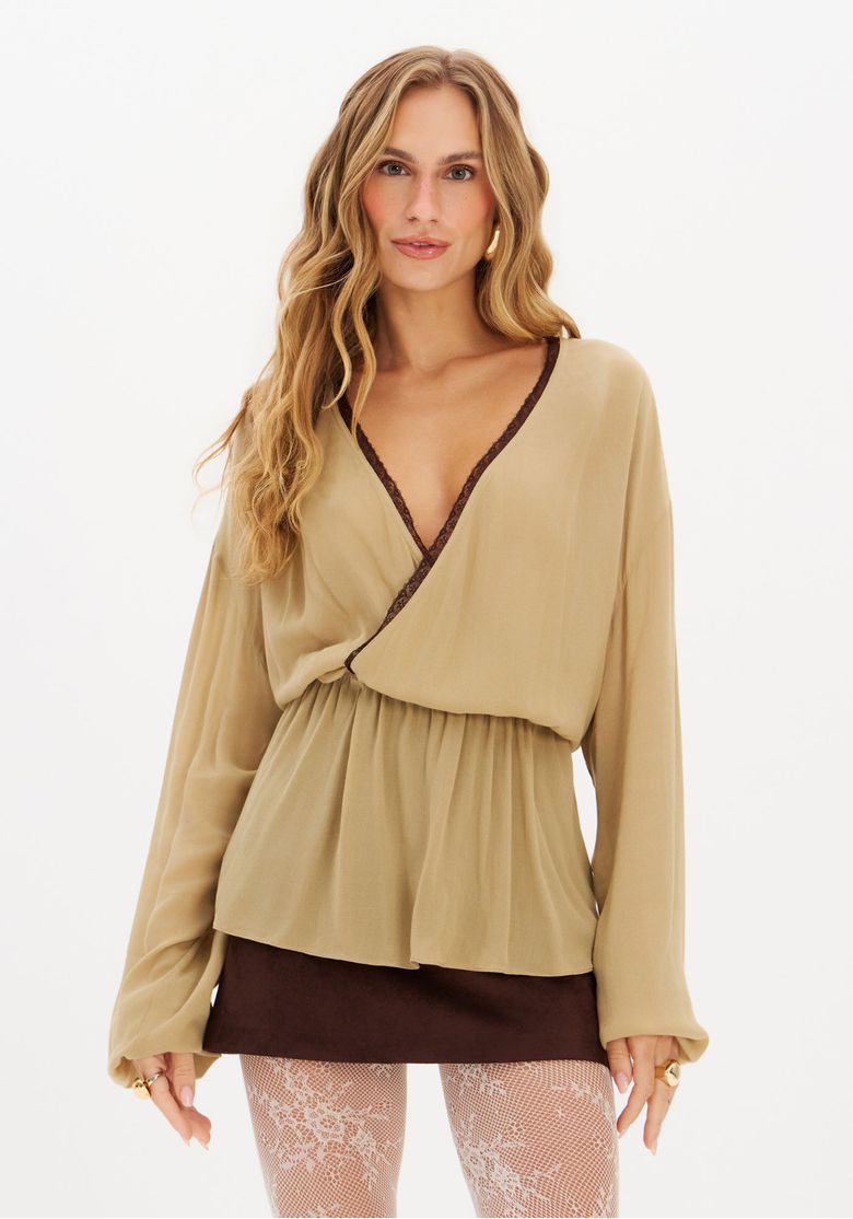 Modelo-usando-blusa-transpassada-bege-com-renda-marrom-decote-em-V-profundo-e-mangas-longas-amplas-vista-frontal-tres-quartos---blusa-transpassada-viscose