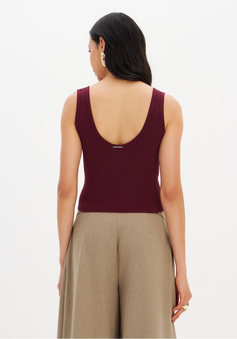 Modelo usando a blusa cropped canelada com calça ampla bege, vista completa do look.