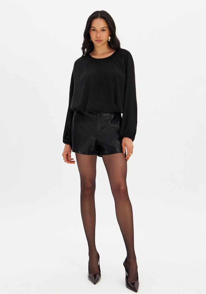 Look completo com blusa balonê preta combinada com shorts efeito couro e meia-calça, styling urbano e sofisticado