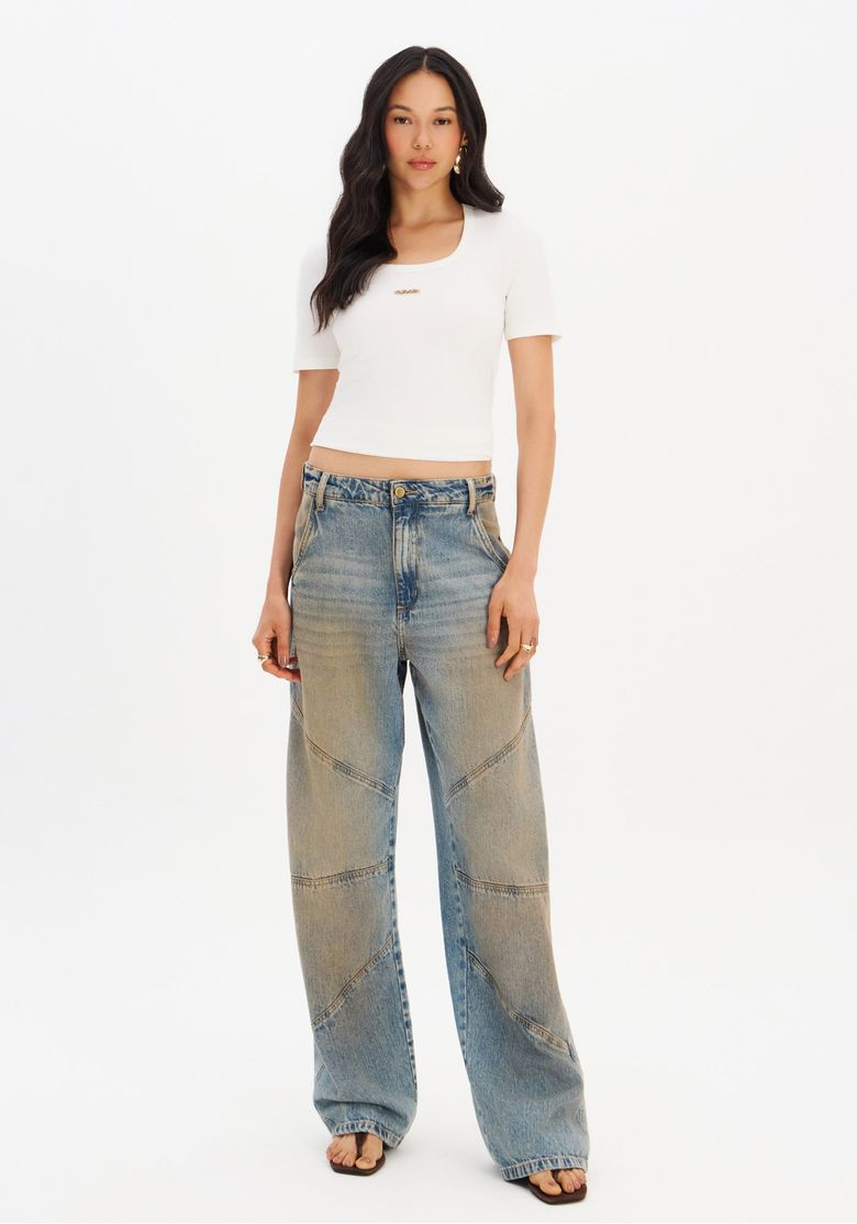 Modelo usando a blusa canelada branca com calça jeans ampla.