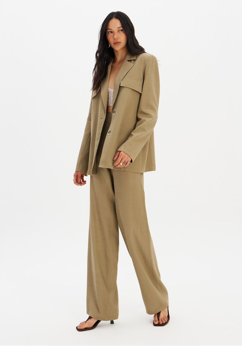 Conjunto com blazer alongado verde e calça ampla combinando, vista em pé mostrando caimento alongado e ombros estruturados