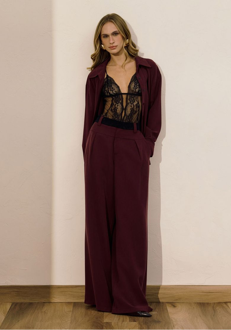 Modelo vestindo a camisa bordô aberta, revelando um look com lingerie por baixo.