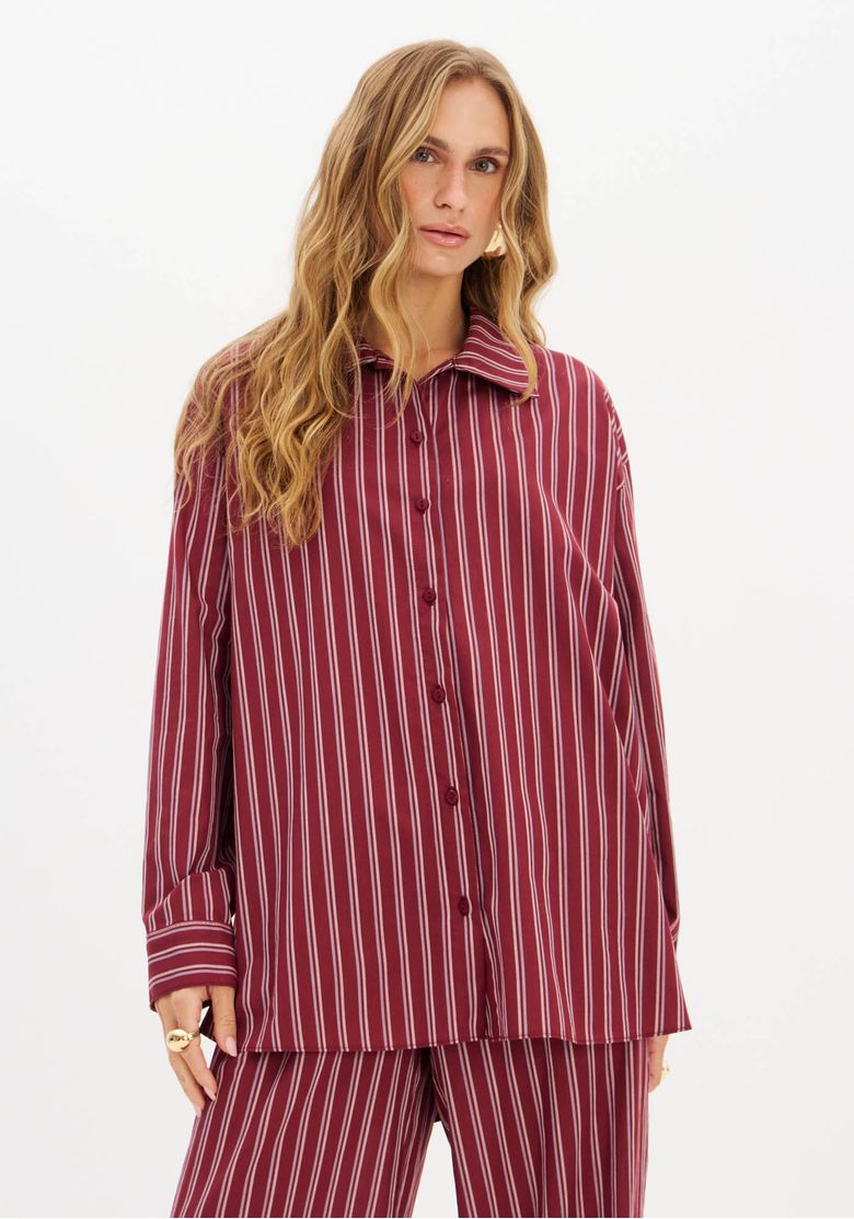 Vista lateral da camisa oversized alongada, destacando o caimento amplo e as listras.