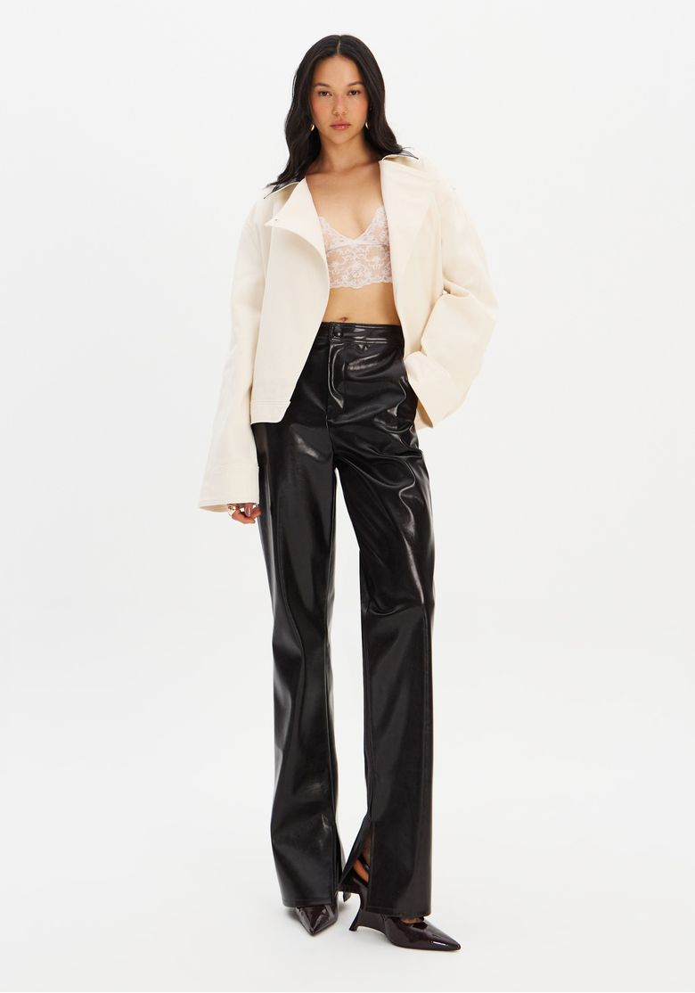 Modelo usando calça boot cut em PU brilhoso com blazer claro.