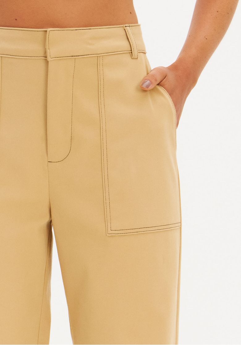 Modelo posando com calça reta utilitária bege, blazer e blusa de renda longa, styling workwear contemporâneo