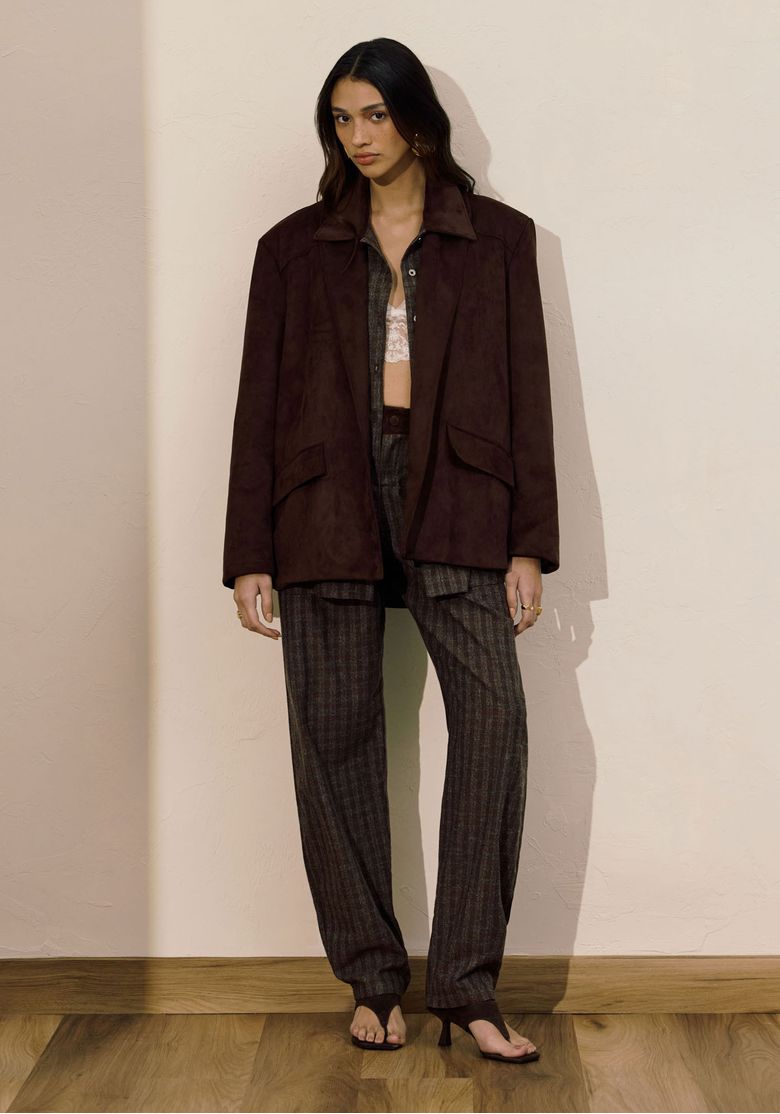 Modelo usando calça barrel xadrez marrom com jaqueta marrom oversized, look completo em ambiente interno - calça barrel xadrez cintura média