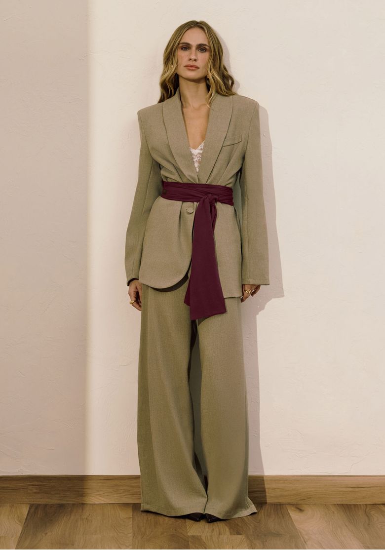 Modelo vestindo calça palazzo verde com blazer combinando em ambiente interno.