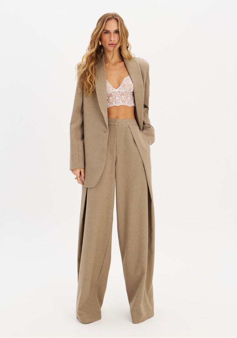 Modelo usando calça palazzo verde com top rendado e blazer em fundo branco.