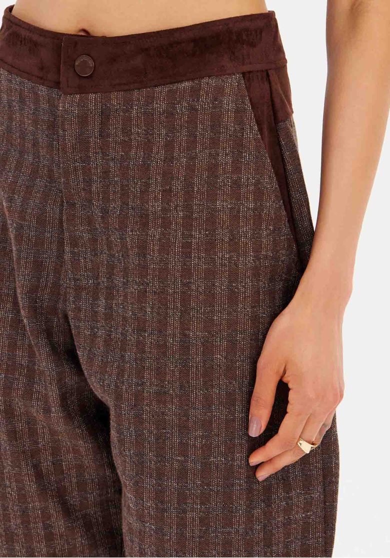 Modelo em estúdio vestindo top tomara-que-caia combinado com a calça barrel xadrez marrom, visual frontalluz branca