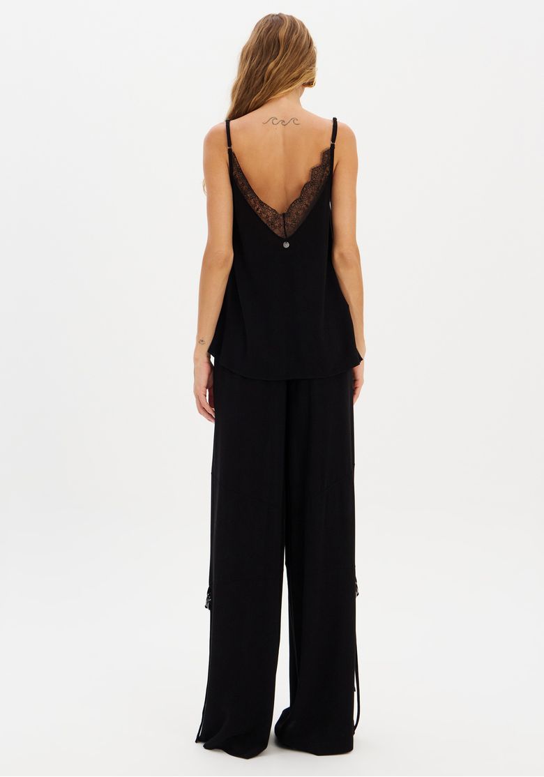 Modelo vista de costas usando top de renda e calça wide leg preta, com cós elástico e caimento solto até a barra
