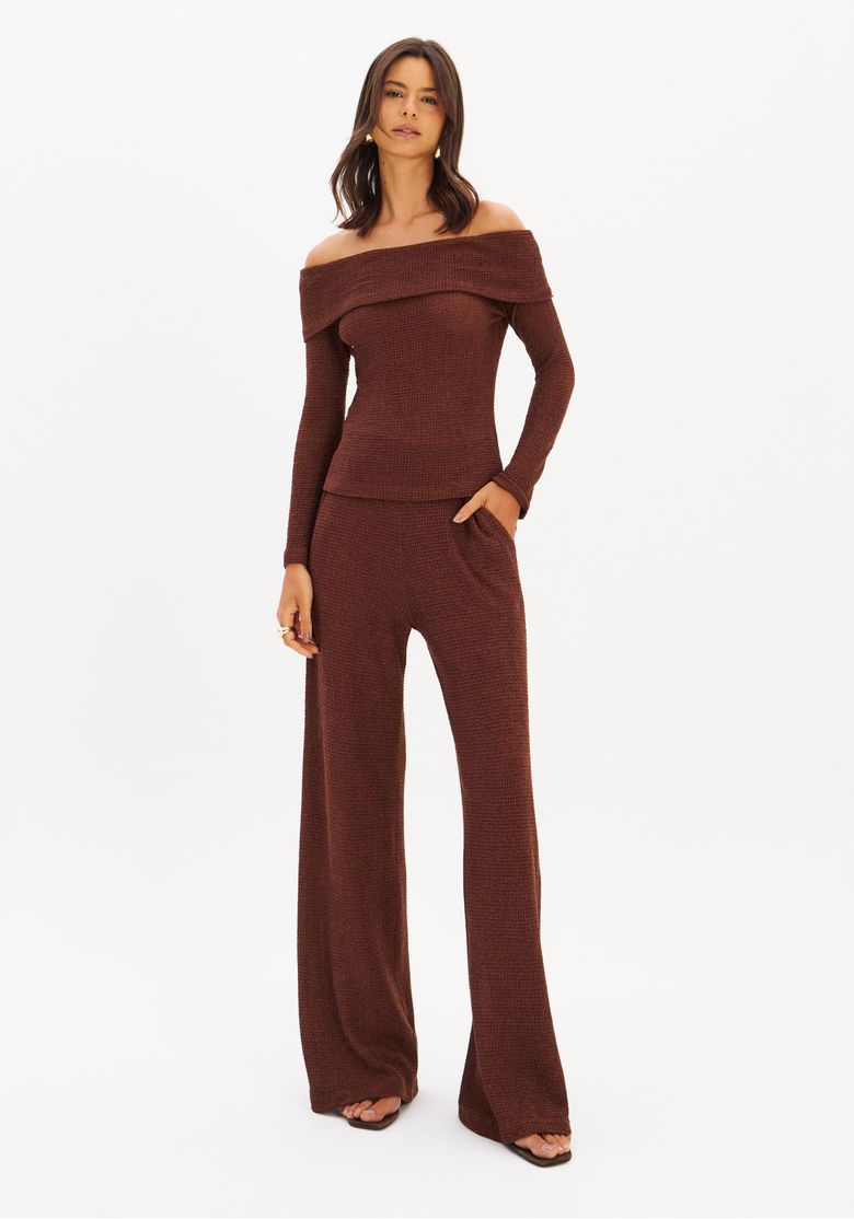 Modelo vestindo calça full length em malha texturizada marrom com top ombro a ombro; vista frontal do look completo com cintura média e comprimento longo.