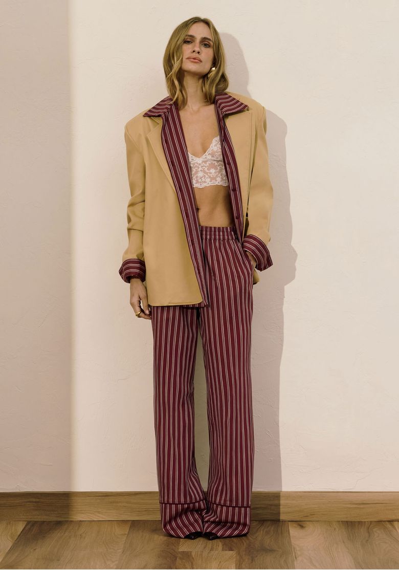 Modelo usando calça full length listrada vermelha com blazer bege e bralette branco; visual frontal mostrando caimento amplo e cintura média com cós elástico
