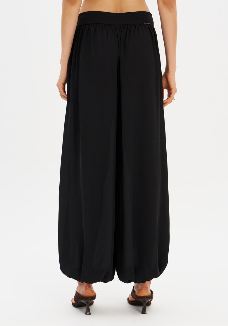 Vista traseira da calça aladim preta com modelagem fluida.