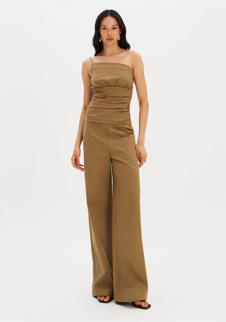 Modelo em pé usando macacão longo ombro único verde, vista frontal com pernas pantalona e alça fina - look casual urbano.