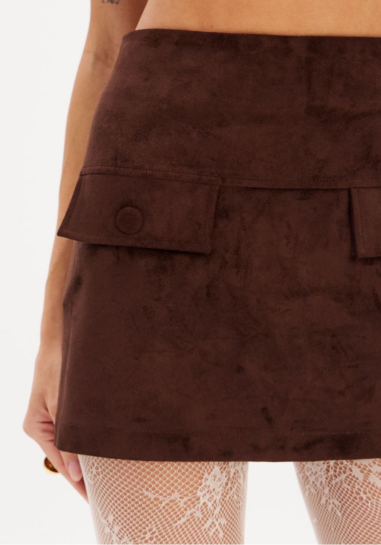 Detalhe dos bolsos frontais da saia curta em suede marrom.