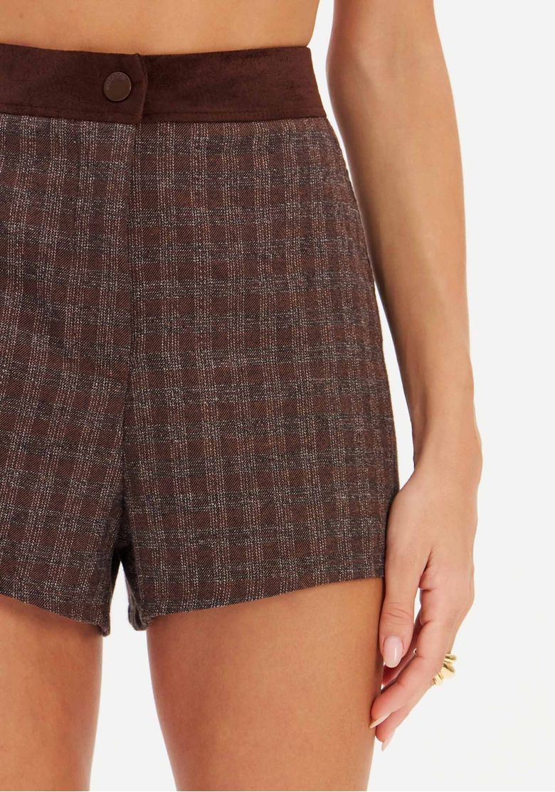 Modelo com blazer aberto sobre short xadrez marrom em estúdio, combinação monocromática em tons terrosos