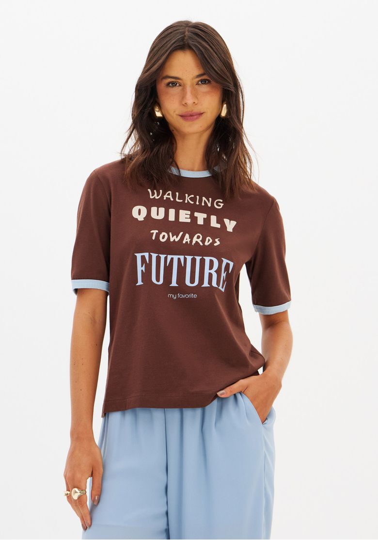 Close-up da camiseta marrom com estampa frontal e detalhes contrastantes.