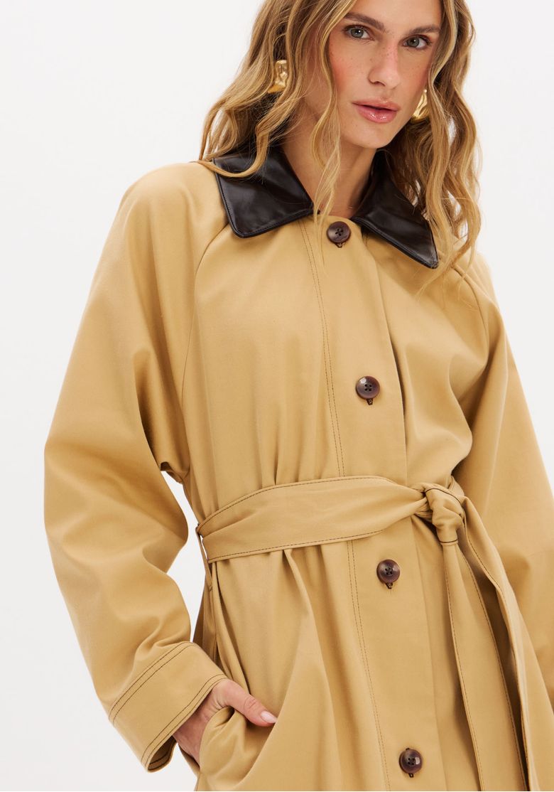 Close-up da gola preta em PU do trench coat bege.