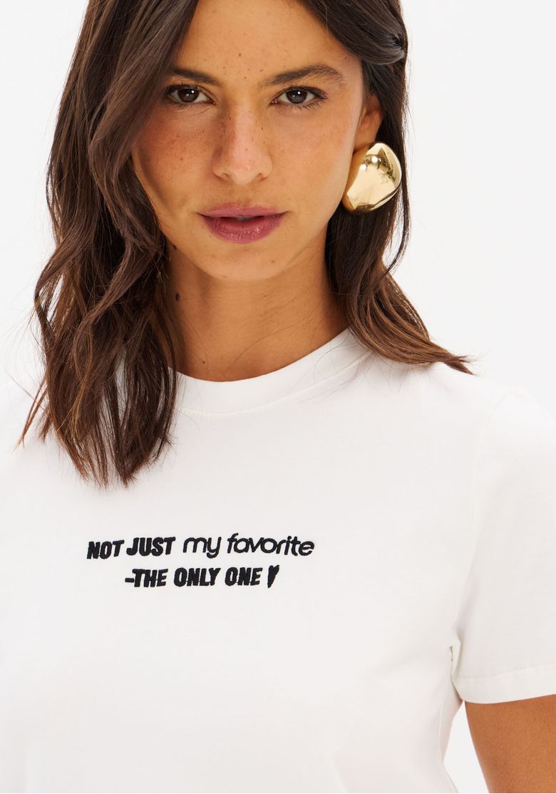 Look completo com camiseta baby look branca bordada e saia preta longa - imagem corpo inteiro mostrando comprimento da camiseta e caimento ajustado