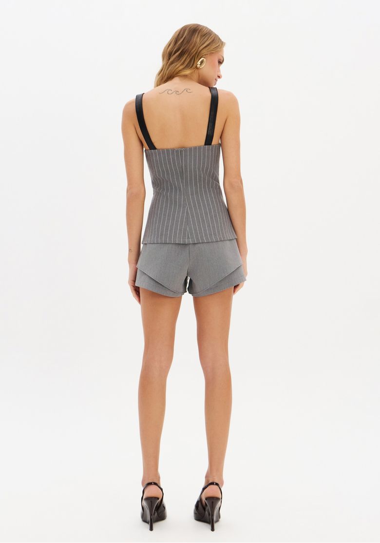 Vista traseira do modelo usando o top corselet e o short cinza, mostrando o fechamento por zíper invisível e alças largas do top.