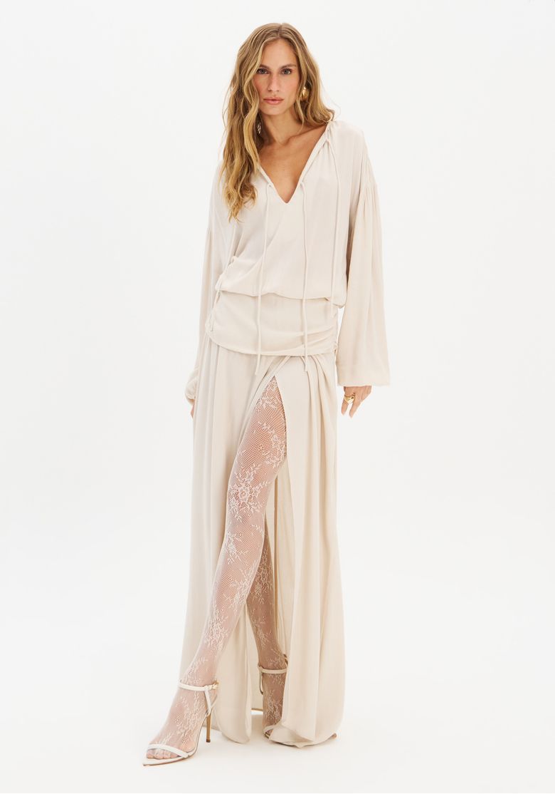 Modelo-em-fundo-branco-exibindo-vestido-longo-crepe-branco-com-fenda-estrategica-e-detalhes-de-amarracao-no-decote