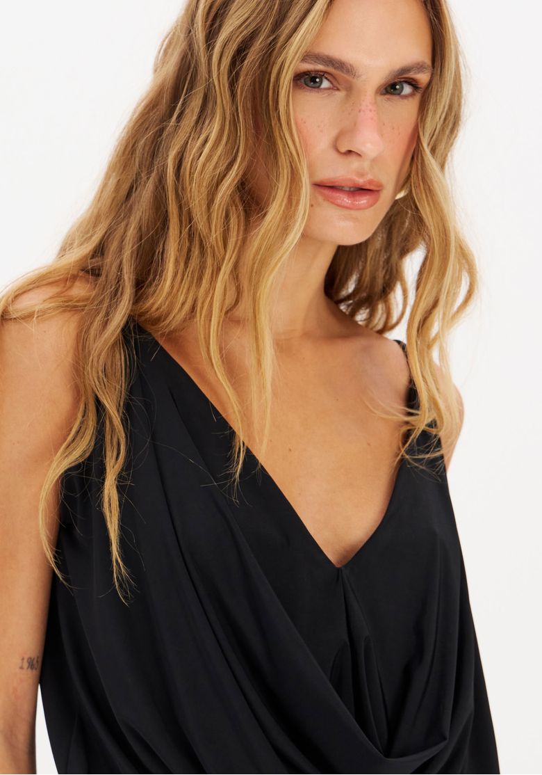 Modelo usando vestido midi preto com meia-calça e scarpin, destaque para decote em V e fenda lateral