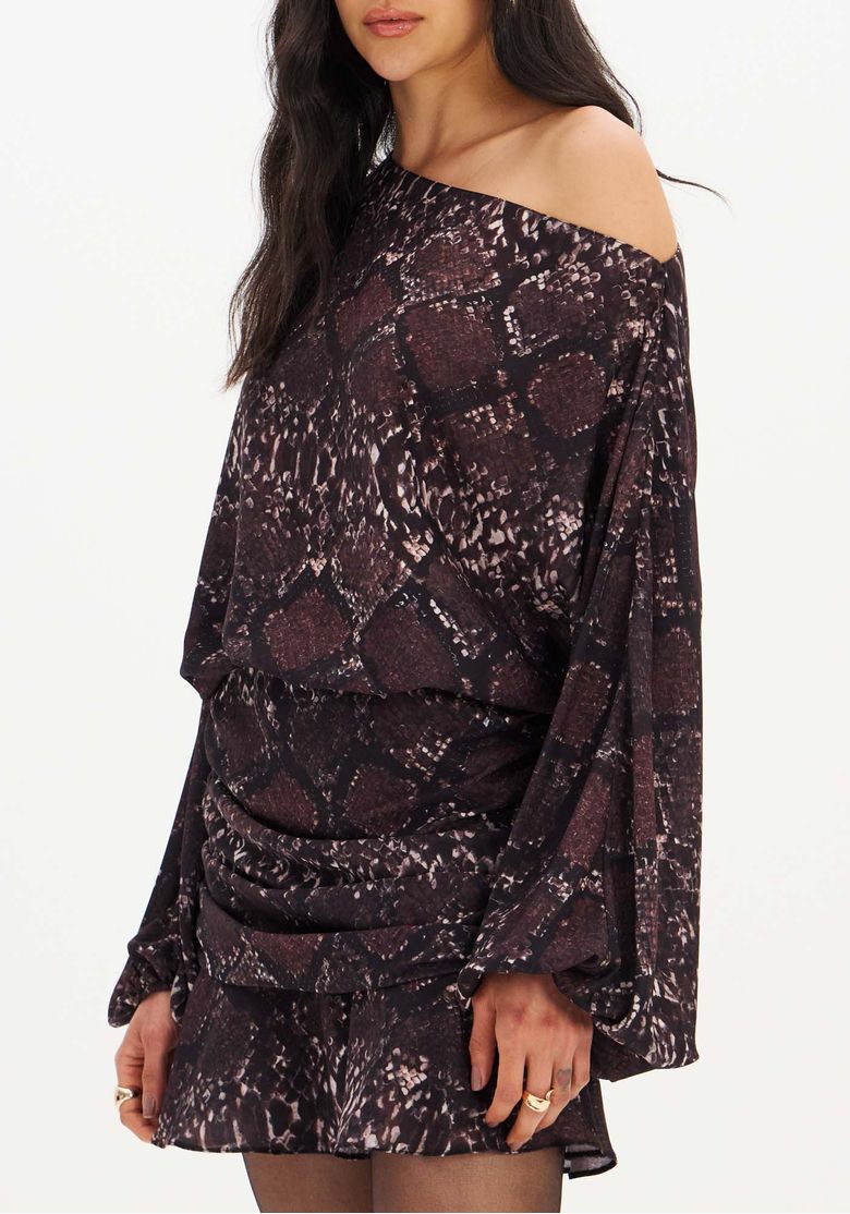 Modelo em fundo branco com vestido curto estampado croco marrom, pose frontal destacando mangas longas e cintura baixa