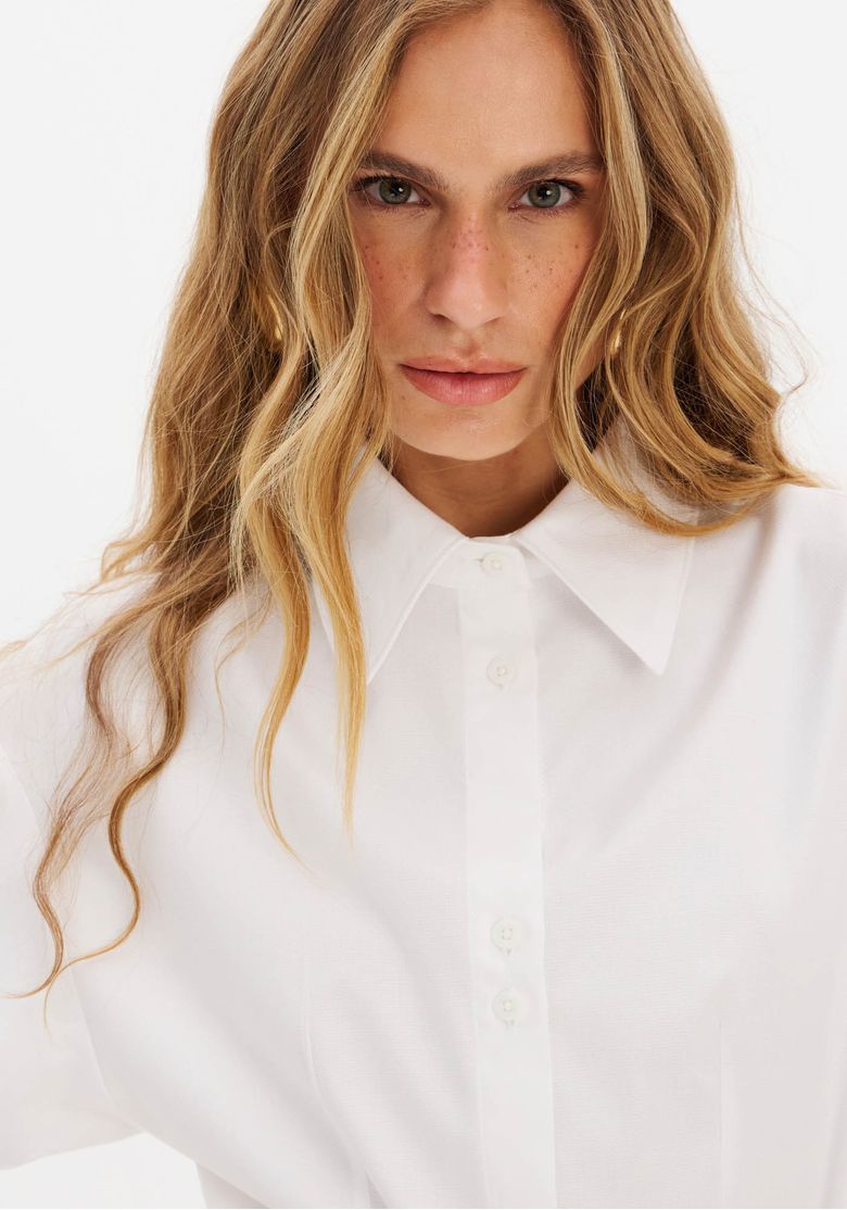 Visual de styling com camisa branca alongada usada sob corset risca-de-giz e shorts, composição de textura e sobreposição