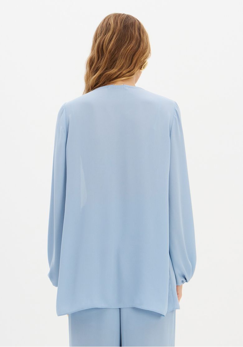 Modelo usando o top azul com renda, combinando com a calça fluida azul.