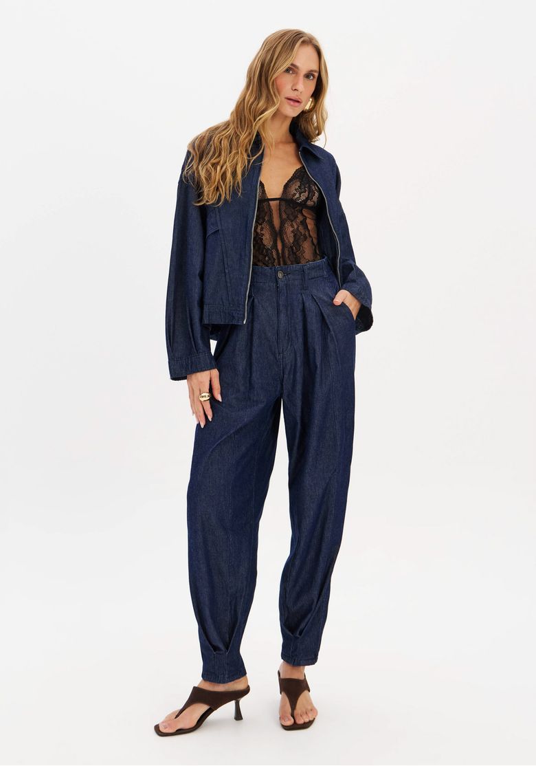Modelo vestindo calça jeans slouchy cintura média lavagem azul escura com jaqueta denim oversized e body de renda, vista frontal mostrando pregas e caimento despojado