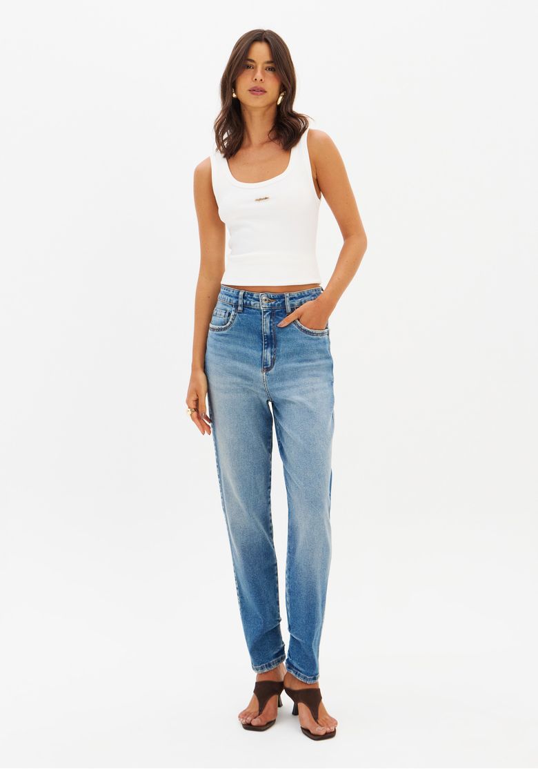 Modelo frontal usando calça jeans Mom cintura alta lavagem clara com regata branca e sandálias, look inteiro