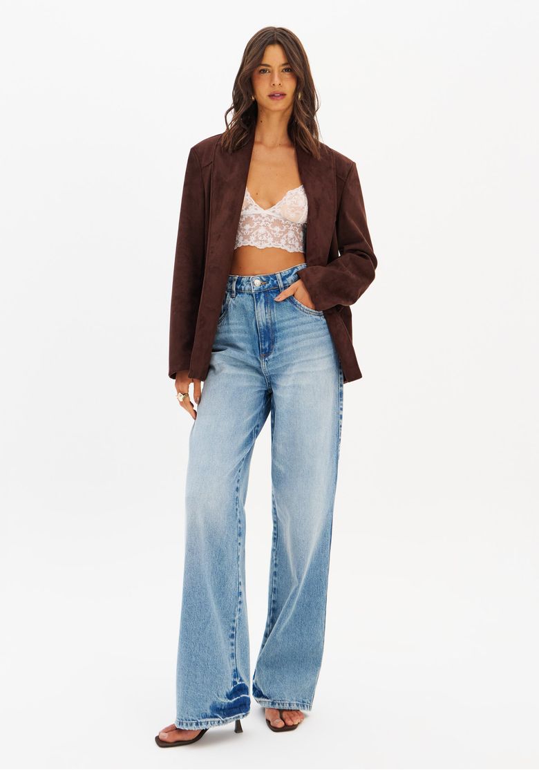 Modelo veste calça jeans feminina cintura alta full length lavagem clara, com blazer marrom e top de renda, look casual chique