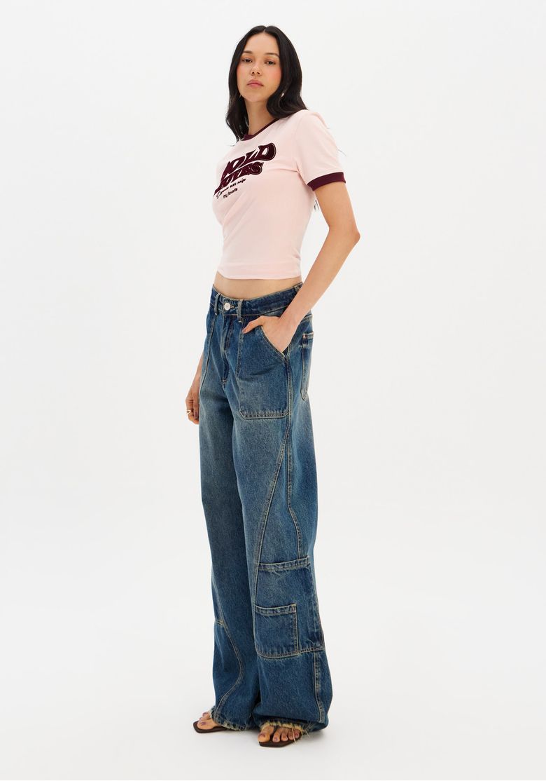 Modelo em pose lateral exibindo a calça jeans barrel leg azul.