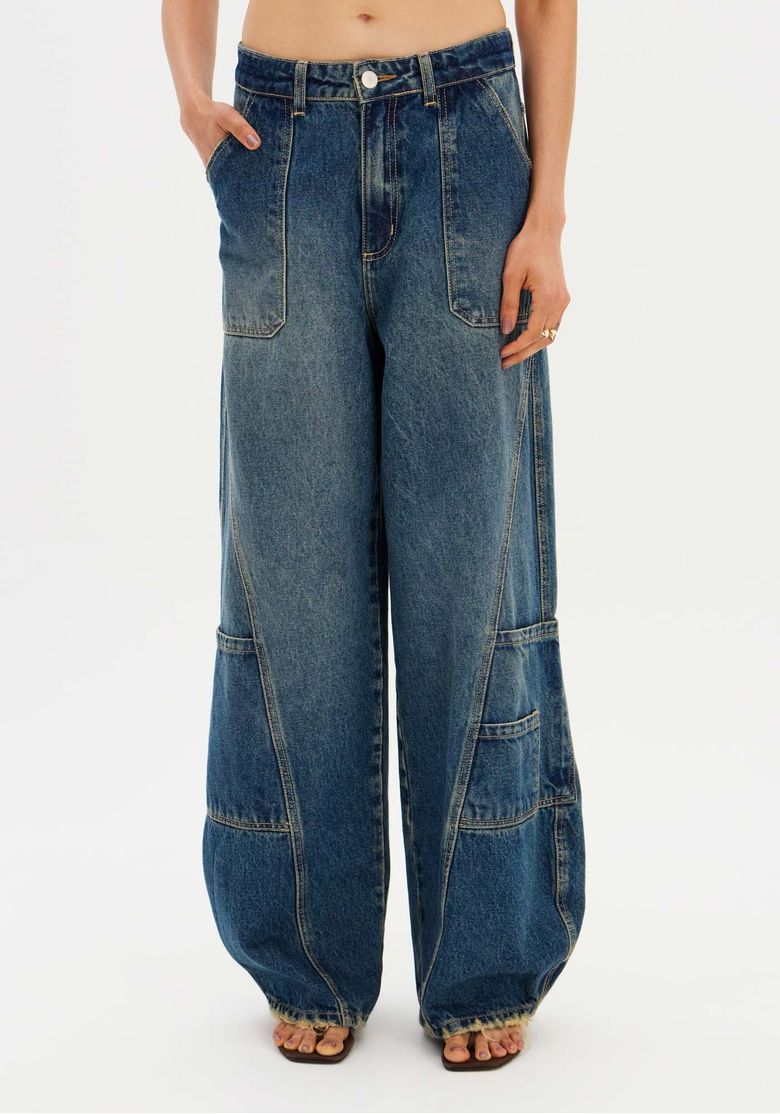 Detalhe frontal da calça jeans barrel leg azul mostrando os bolsos e o cós.