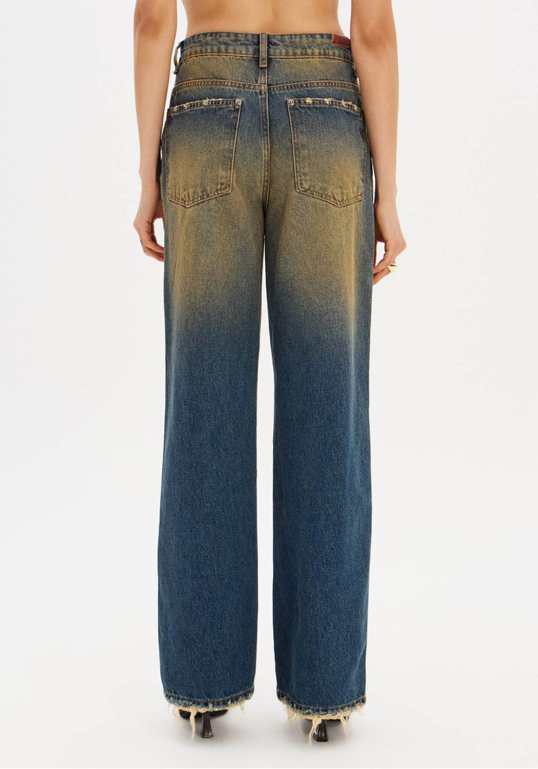 Modelo usando calça jeans full length lavagem estonada degradê com camiseta bege oversized e sandália, look casual com toque vintage