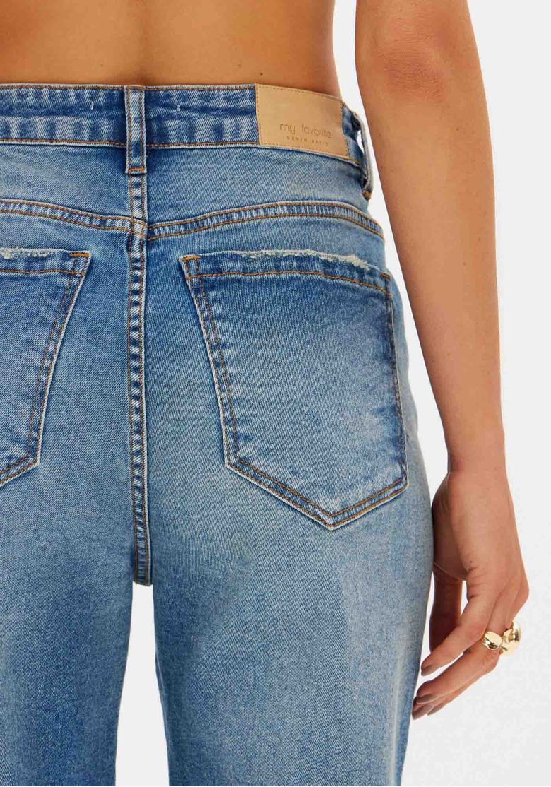 Detalhe dos bolsos traseiros e do cós com etiqueta, costura contrastante e textura do denim