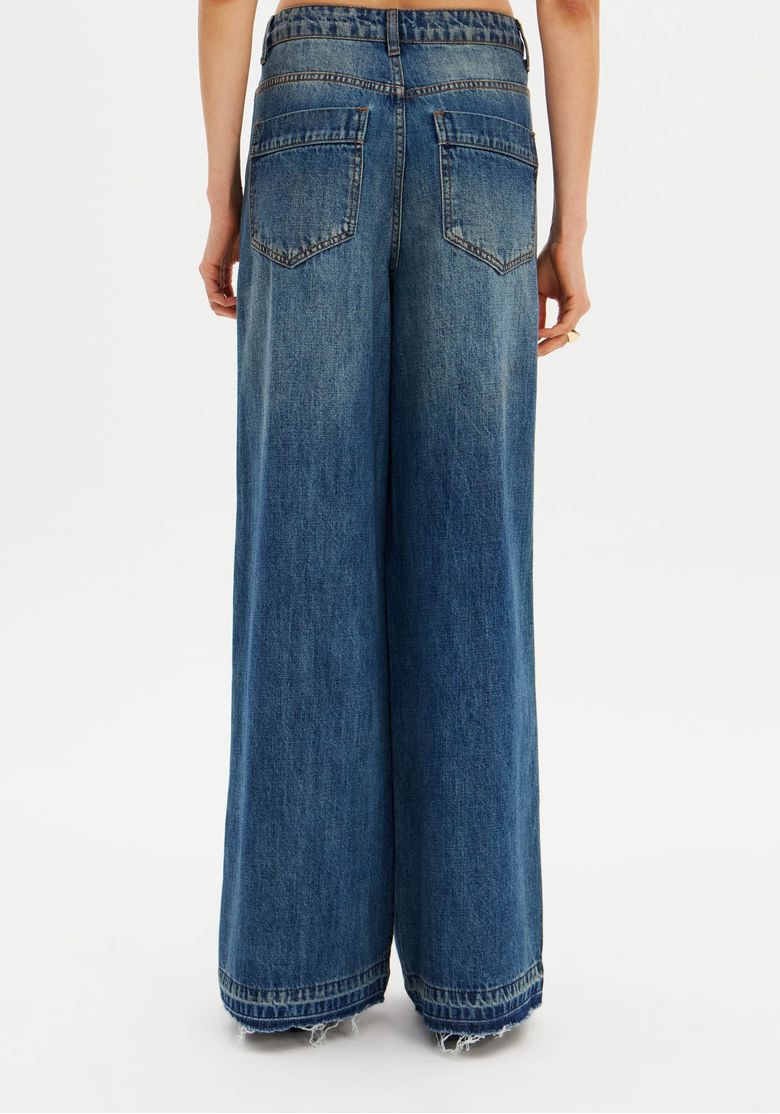 Detalhe traseiro da calça jeans relaxed em denim azul mostrando bolsos posteriores e acabamento da barra