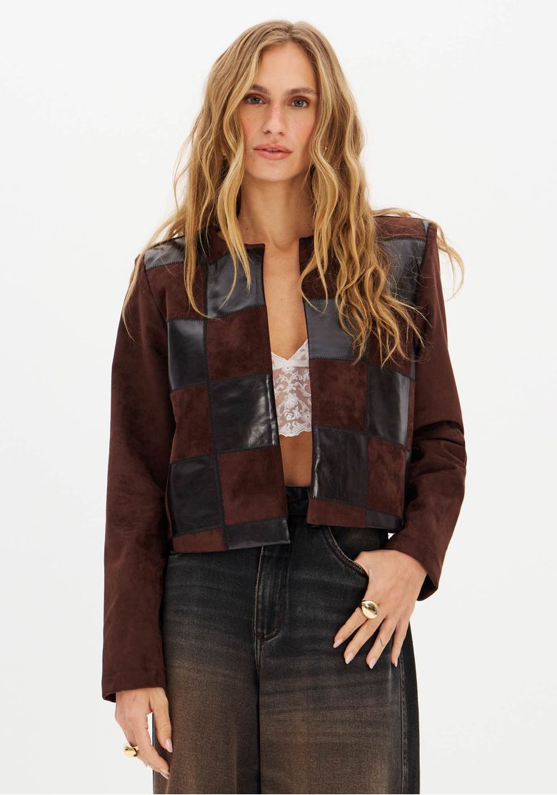 Frente inteira: modelo usando casaco suede marrom com bordado patchwork frontal em quadrados de suede e PU, comprimento médio e caimento descolado, look com calça jeans wide-leg