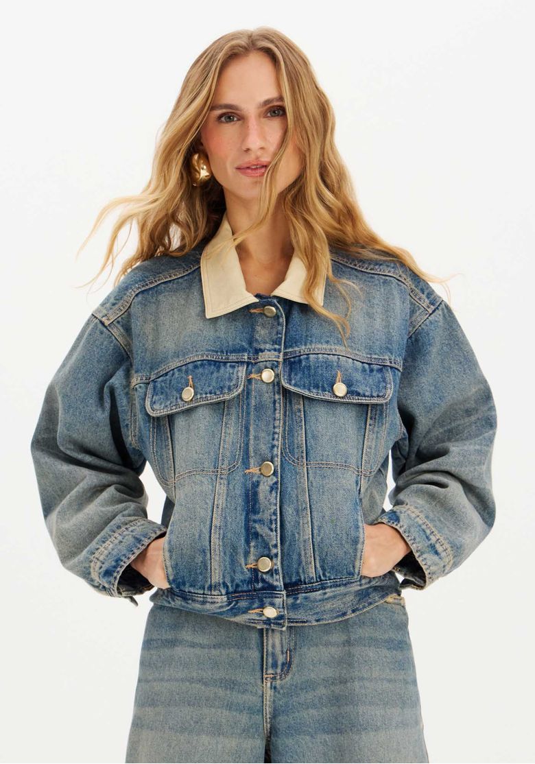 Modelo usando a jaqueta jeans com calça combinando.