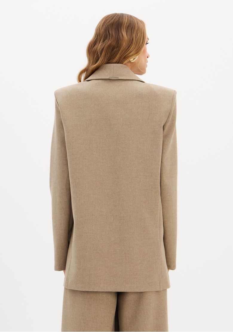 Visão traseira do blazer oversized de alfaiataria destacando ombreiras pronunciadas e queda alongada