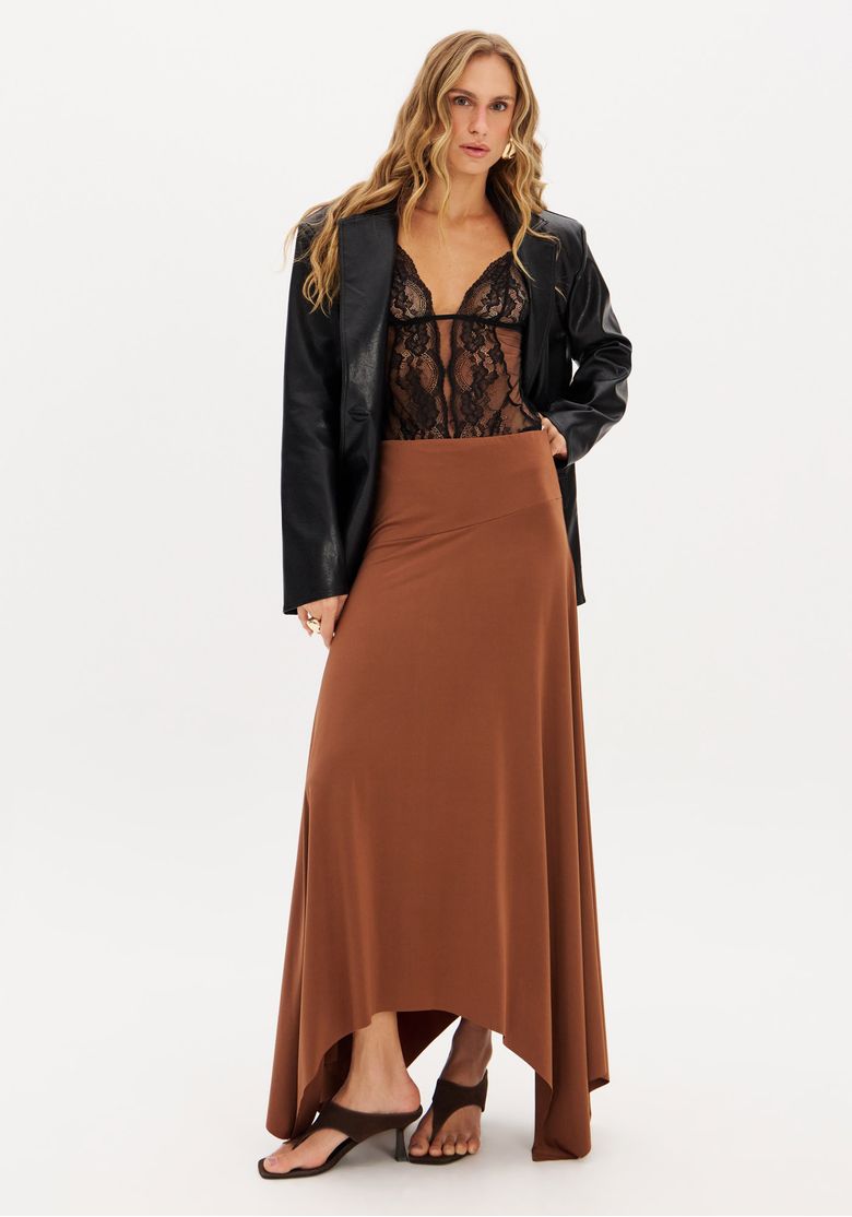 Modelo vestindo saia super midi marrom com barra assimétrica, combinada com top preto e blazer.